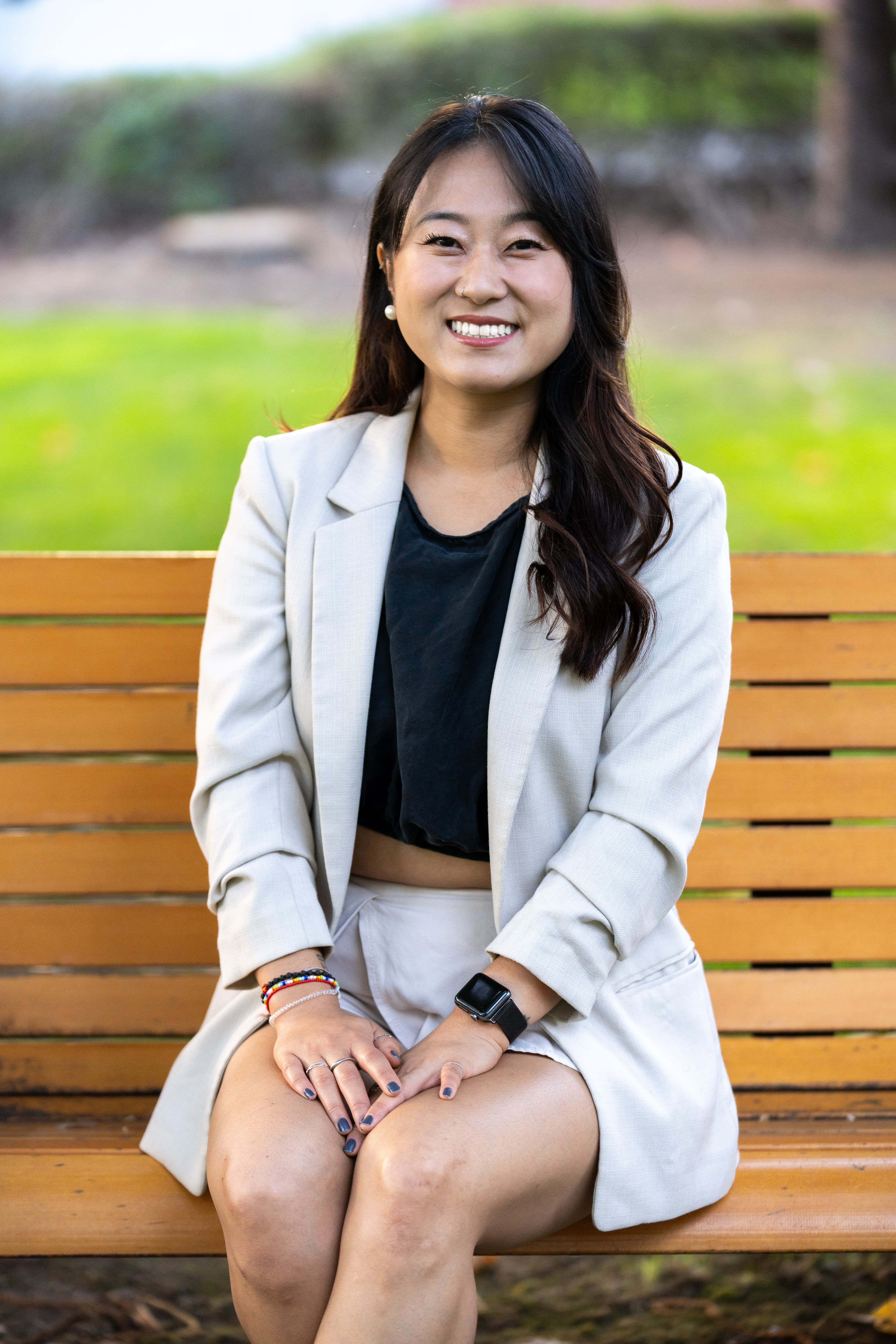 Kate Mayne smiling, seated on a wooden park bench